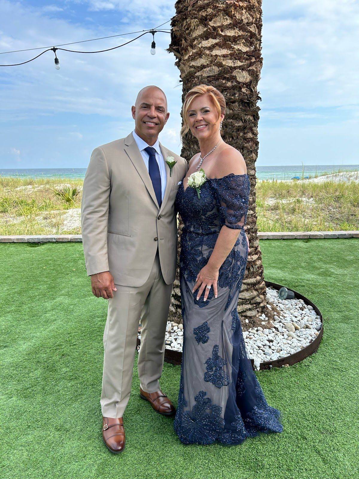 Two guests in tailored formalwear, including a fitted lace gown, at an evening event